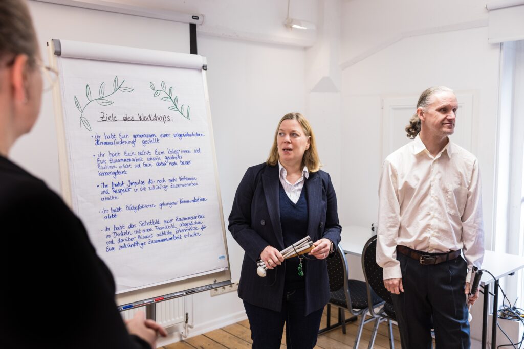 Zwei Mitarbeitende des Dialoghauses stehen in einem inklusiven Workshop neben einer Flipchart.