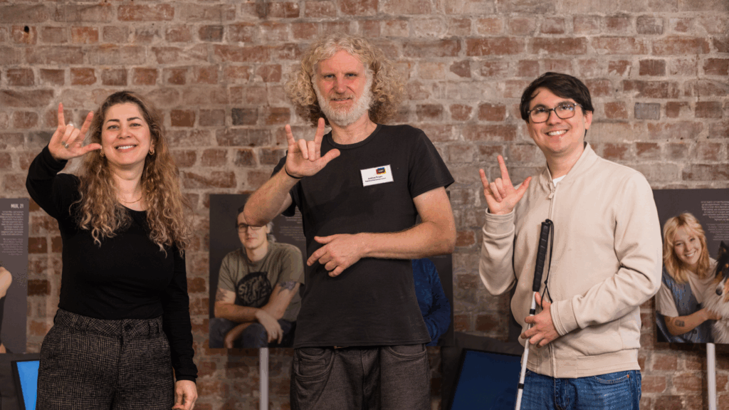 3 Mitarbeitende des Dialoghaus Hamburg zeigen die "Ich liebe dich"-Gebärde in die Kamera.